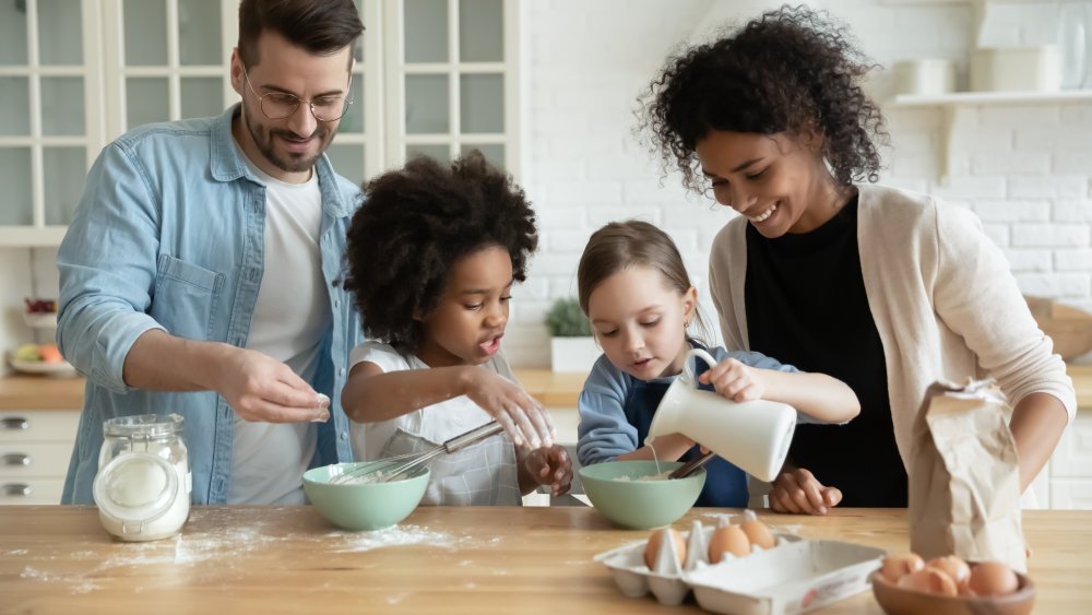 A family of four baking and pouring milk