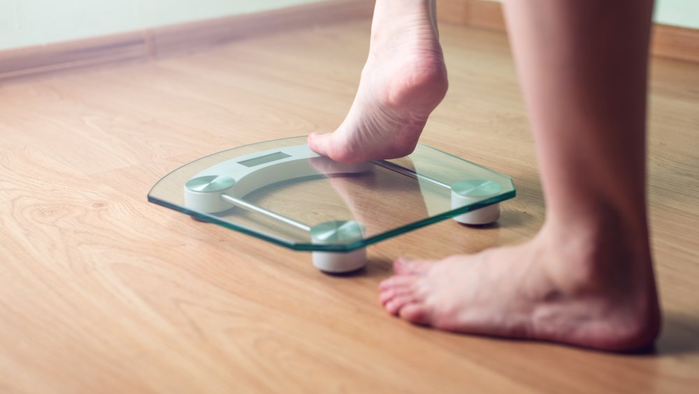 Woman getting on weighing scales