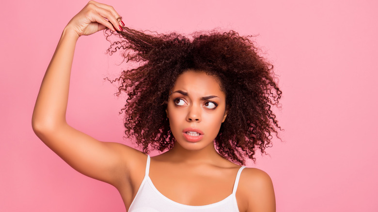 woman holding a strand of her curly hair 