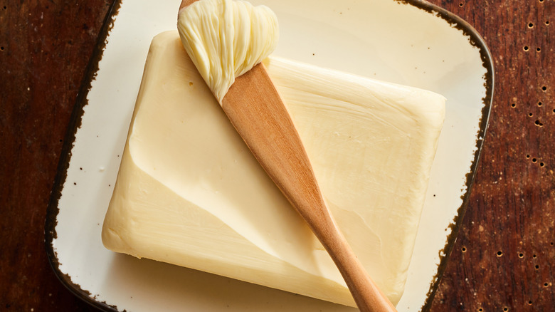 A slab of butter with a wooden spreader