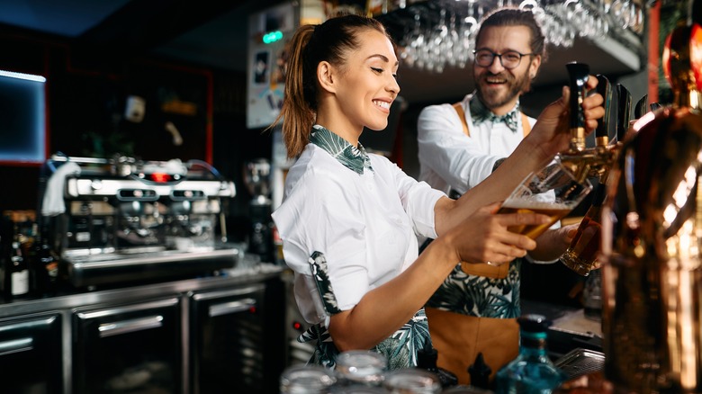 Bartenders smile while preparing beer for customers