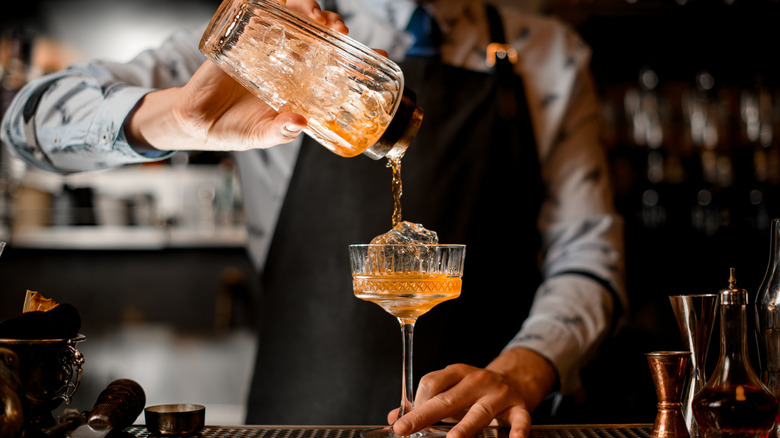 Bartender pours colorful cocktail