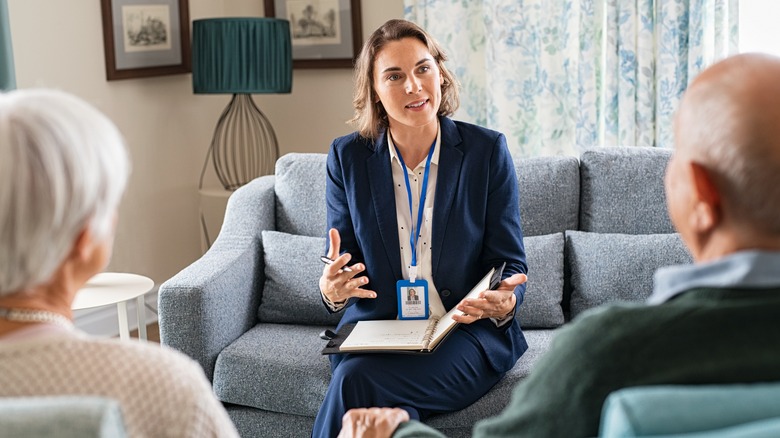 Social worker talks with elderly couple in living room