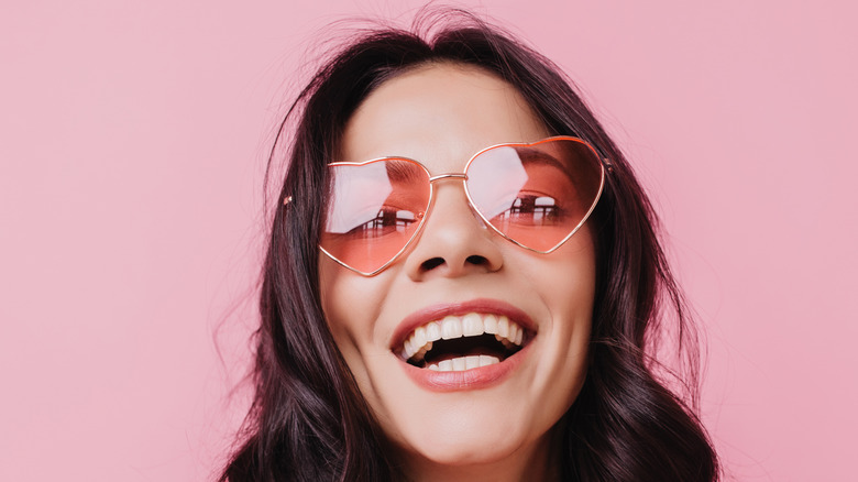 Woman smiling with heart-shaped sunglasses