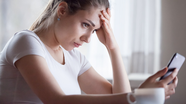 woman looking frustrated at phone