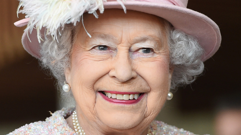 Queen Elizabeth smiling in a pink hat