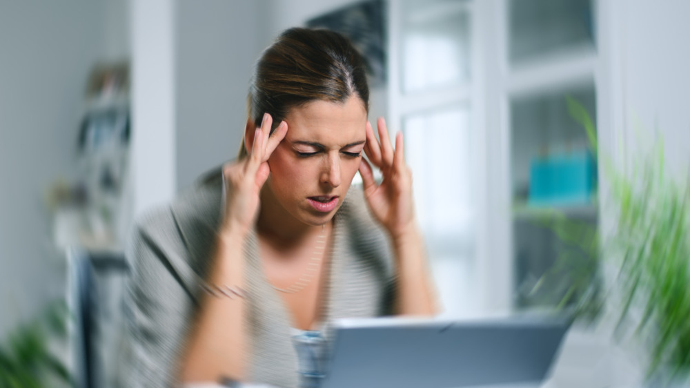 Woman at computer rubbing temples 