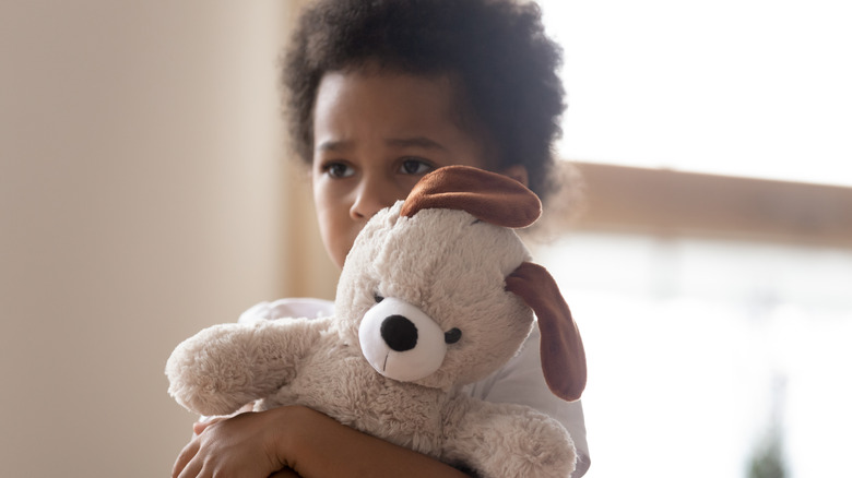 sad little girl holding stuffed animal