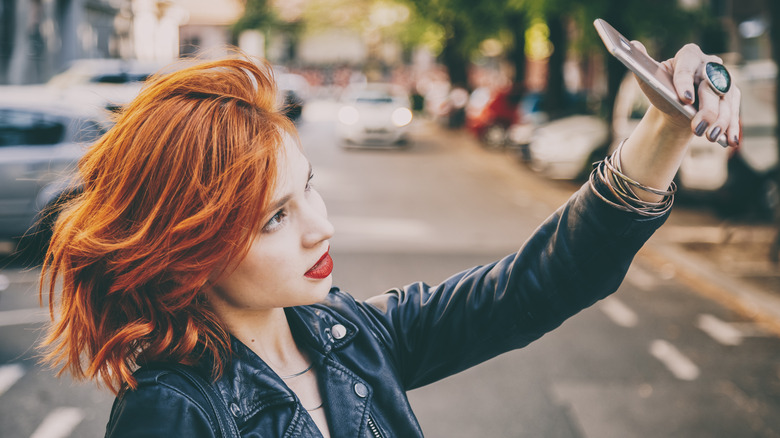 Woman with vibrant copper hair takes a selfie