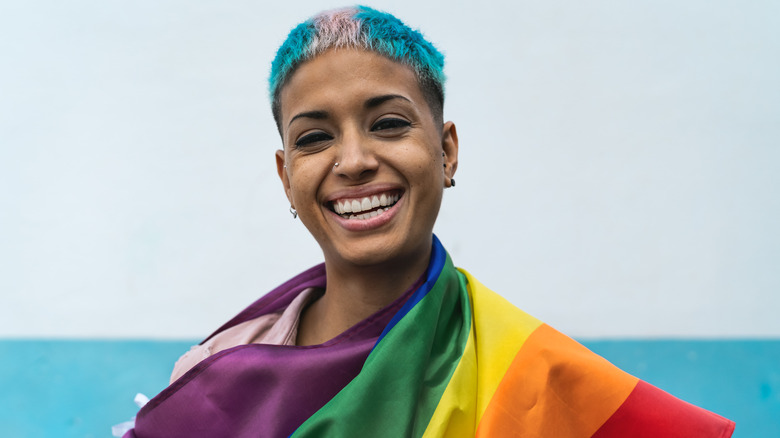 A pweson smiling while wrapped in a pride flag