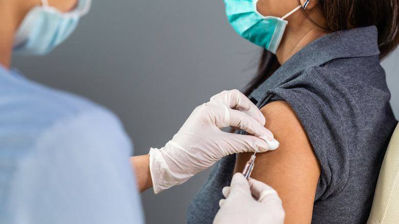 Masked healthcare worker vaccinating patient