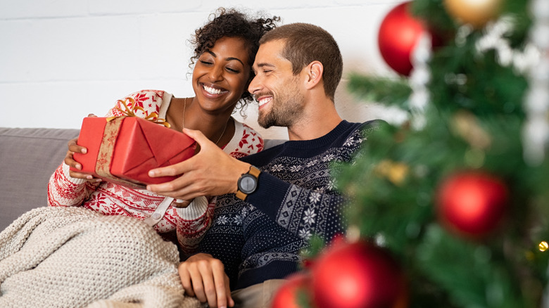 Couple smiling by a Christmas tree 