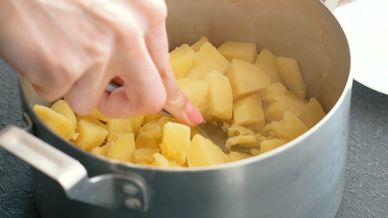Woman mashing potatoes with fork