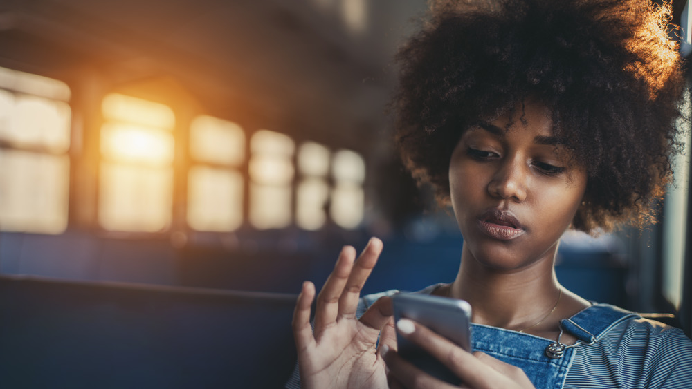 Young woman sitting on the bus using her phone 