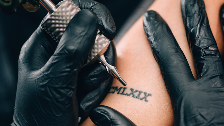 Woman getting a roman numeral tattoo