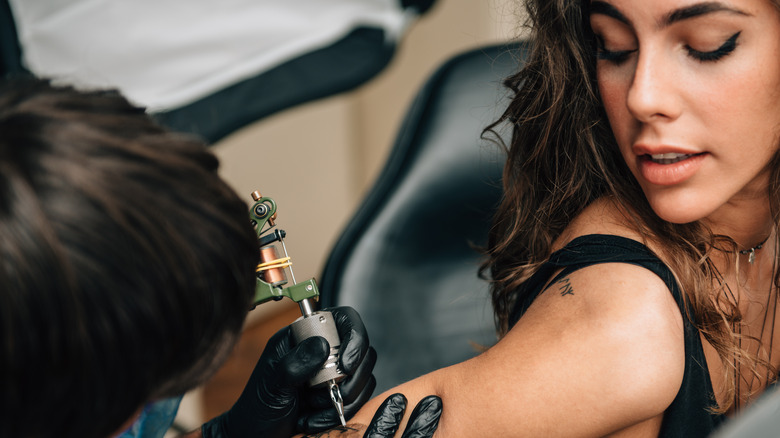 Woman getting tattooed on her arm 