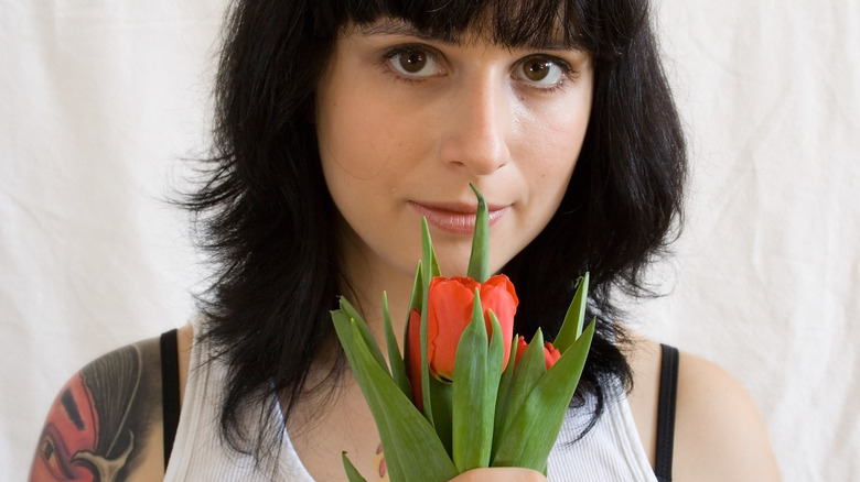 Woman with tattoos holding a red tulip