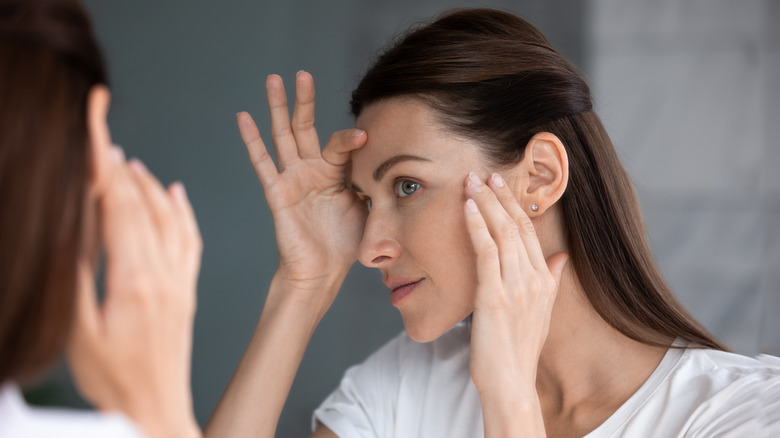 Woman looking at skin in mirror