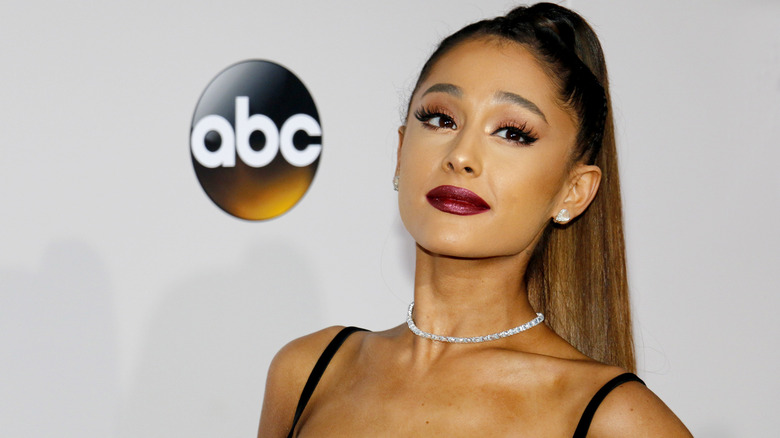 Ariana Grande grinning with bright lipstick hair in pony