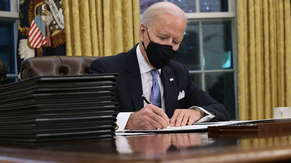 President Biden signing executive orders in mask