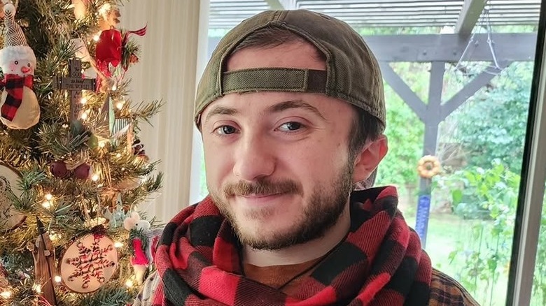 Close-up of Atticus Shaffer smiling next to a Christmas tree