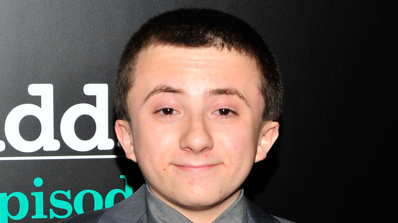 Close-up of Atticus Shaffer smiling on ste-and-repeat
