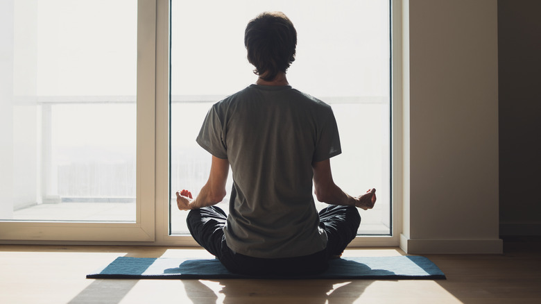 man meditating in front of a window