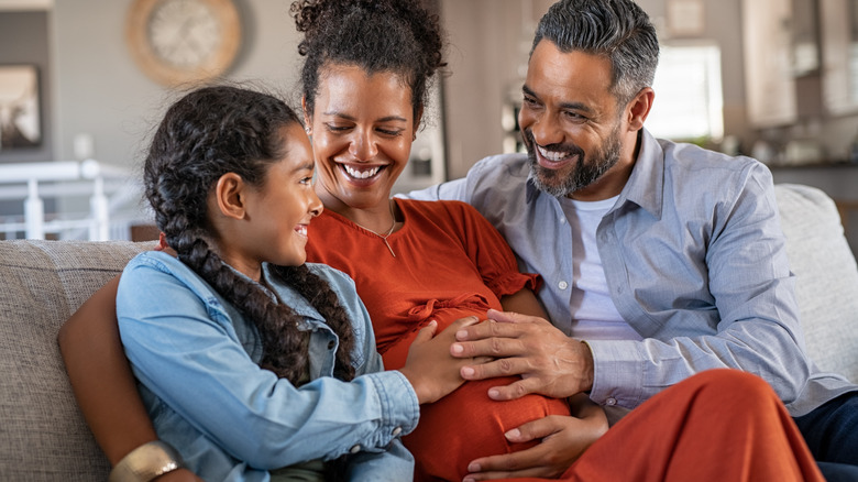 Family touching mother's pregnant stomach