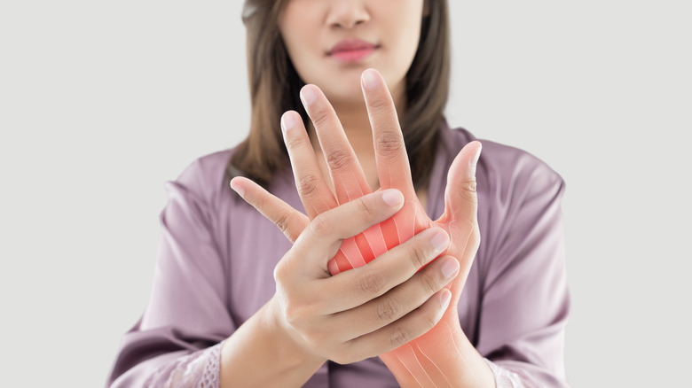 Brunette woman wearing purple shirt rubbing her fingers.