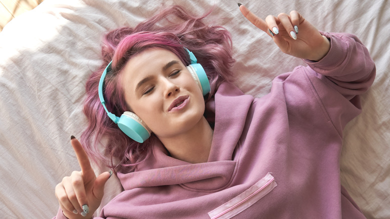 Pink-haired woman smiling to music