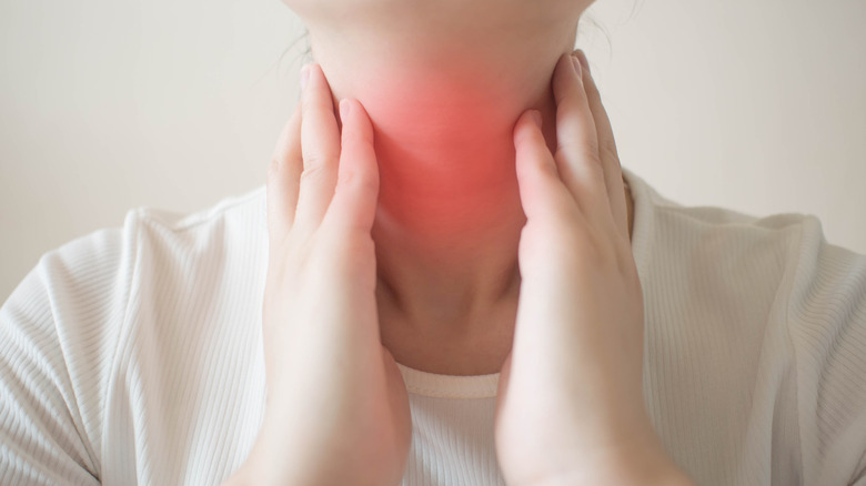 Hands touching swollen lymph nodes on neck