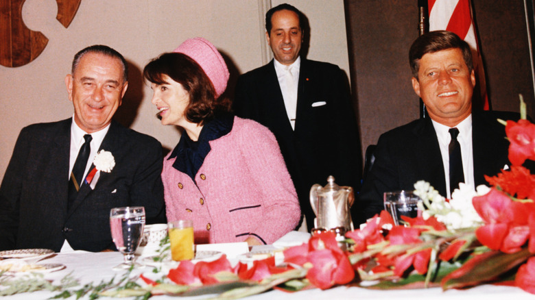 Vice President Lyndon B. Johnson and Jackie Kennedy speaking over breakfast next to President John F. Kennedy