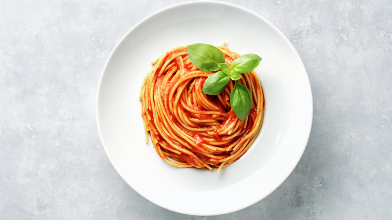 Spaghetti and marinara with basil in a white bowl