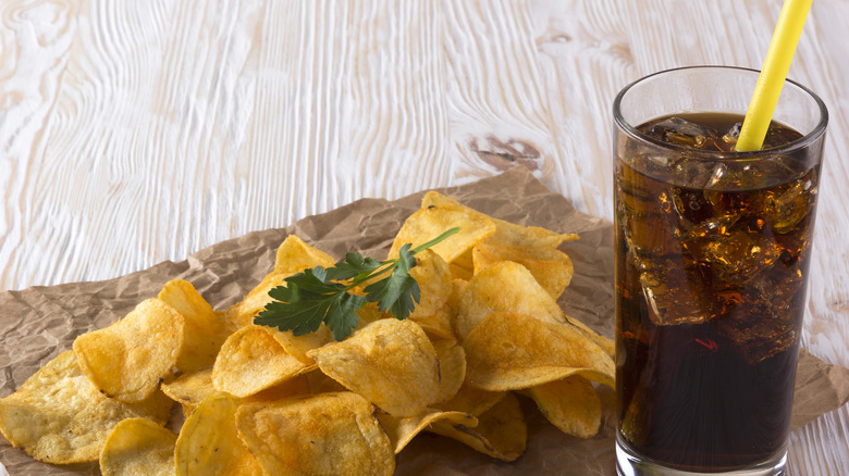 Potato chips and a soft drink on a wooden table