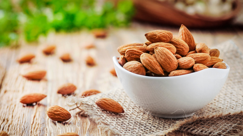 A bowl of almonds on burlap and wood
