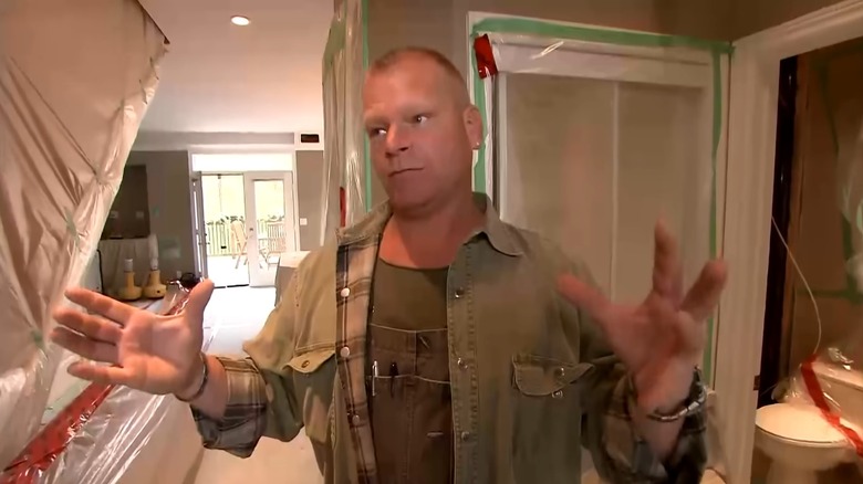 Mike Holmes gesturing with his hands inside a home under construction