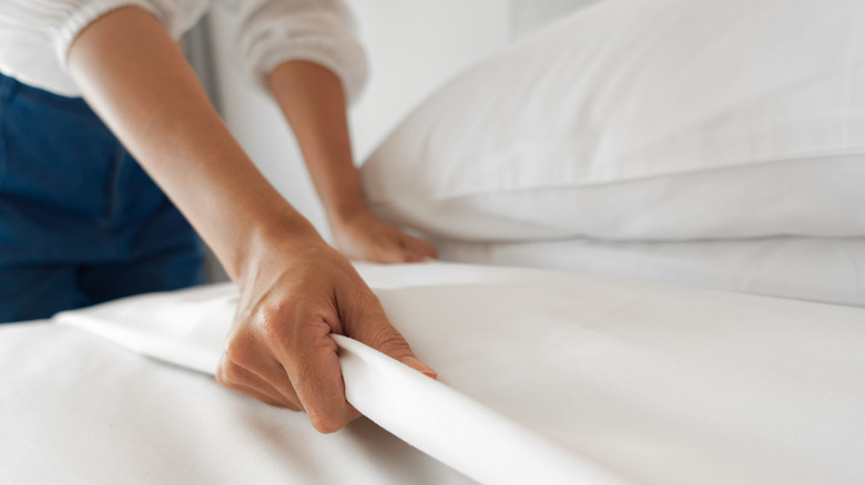 Woman putting sheets on bed