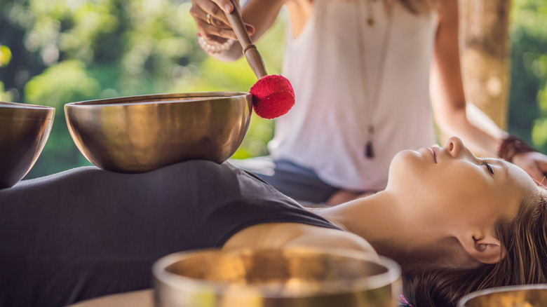 Woman playing a singing bowl on a person's body