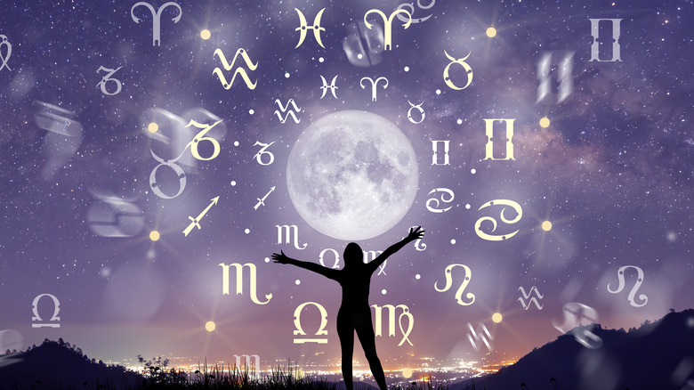 Astrological signs and a full moon with a woman's silhouette in the foreground