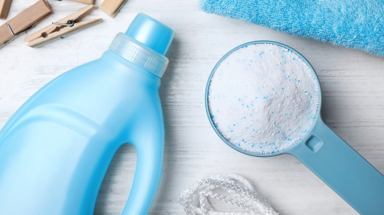 Blue liquid and powdered laundry detergent on a light-colored counter