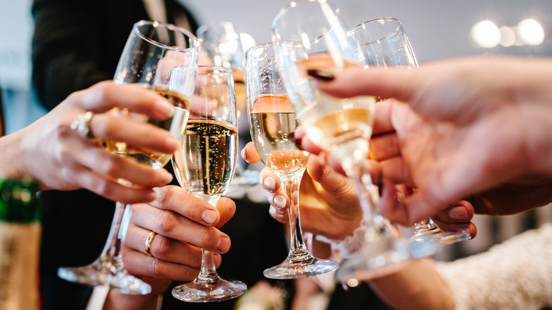 Group of hands raising champagne glasses