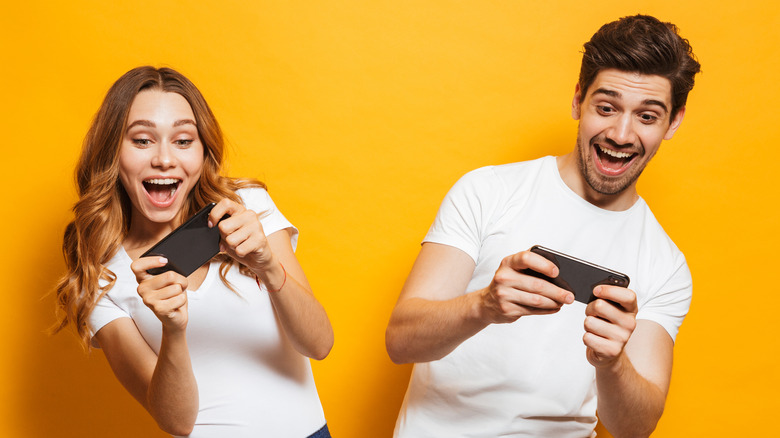 A young couple playing games on their smartphones 