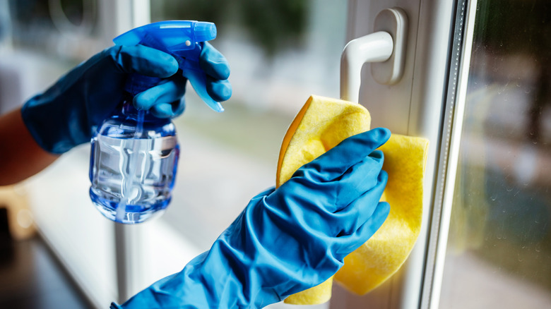 Gloved hands cleaning window handle
