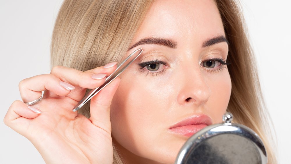 Woman plucking eyebrows