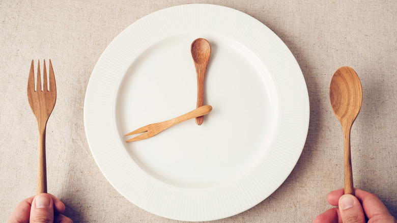 White plate with wooden fork and spoon arranged like a clock.