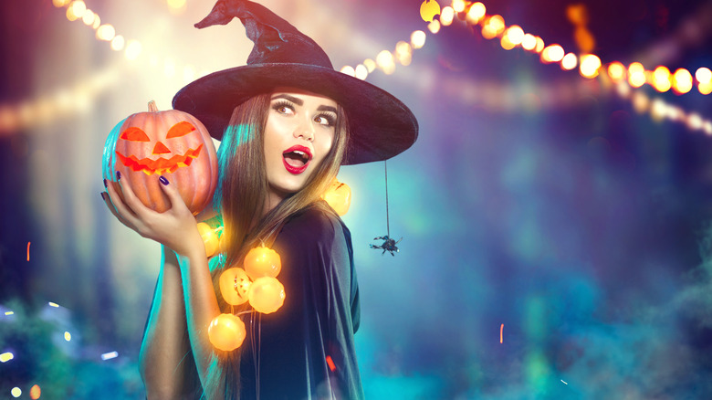 Woman dressed as a witch holding a pumpkin 