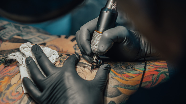 Tattoo artist with tool and rubber gloves
