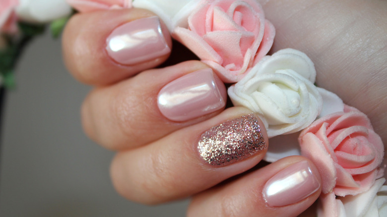 Close up of pink and gold square nails holding roses. 