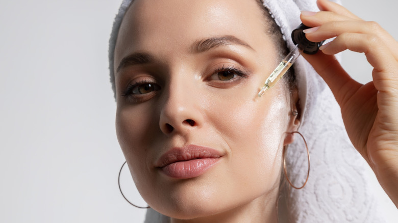 Woman applying facial oil 