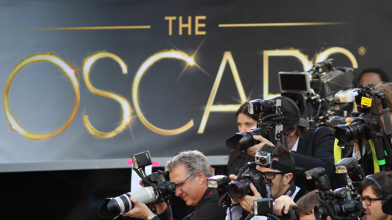 Photographers swarm the red carpet against a backdrop of Oscars signage